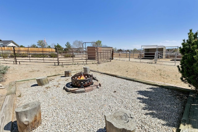view of yard with an exterior structure, a rural view, and an outdoor fire pit