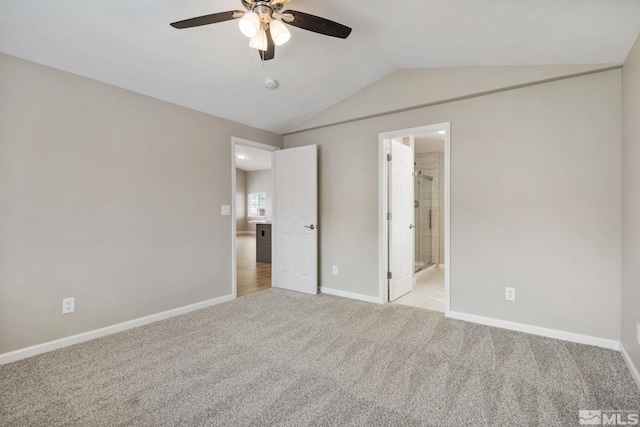 unfurnished bedroom with a ceiling fan, ensuite bathroom, baseboards, light colored carpet, and lofted ceiling