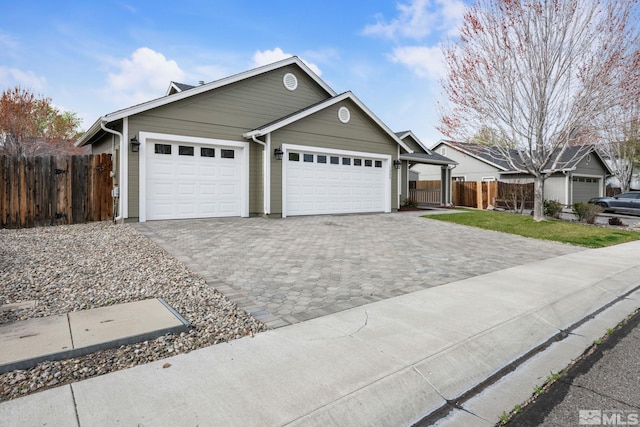 ranch-style home with a garage, fence, and decorative driveway