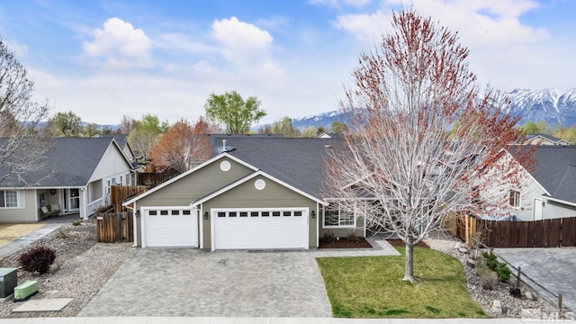 view of front facade featuring fence, an attached garage, driveway, a front yard, and a mountain view