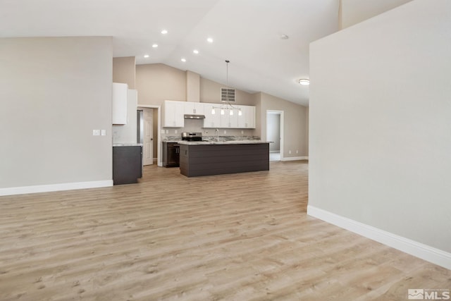 kitchen featuring white cabinets, open floor plan, light countertops, under cabinet range hood, and high vaulted ceiling
