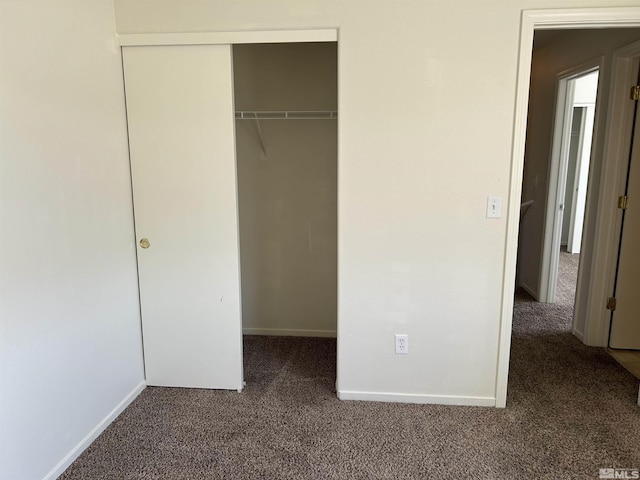 unfurnished bedroom featuring baseboards, carpet floors, and a closet