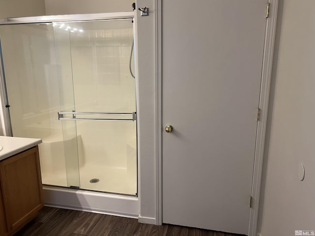full bath with wood finished floors, vanity, and a stall shower