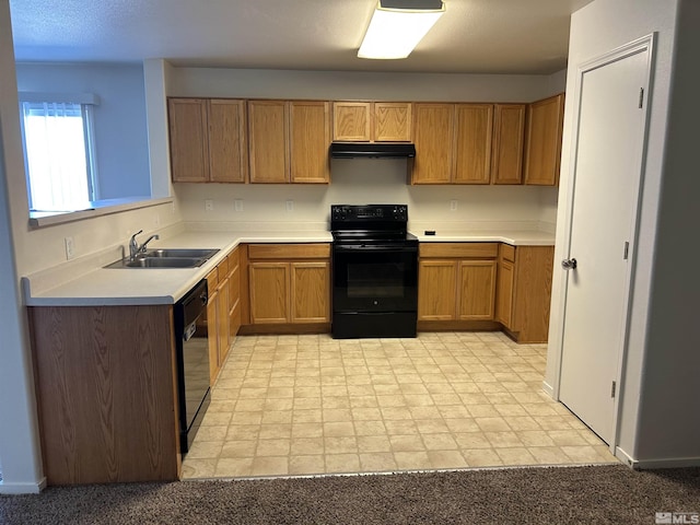 kitchen with a sink, brown cabinets, light countertops, under cabinet range hood, and black appliances