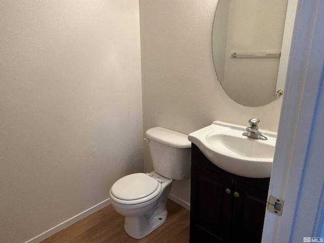bathroom with baseboards, wood finished floors, toilet, and vanity