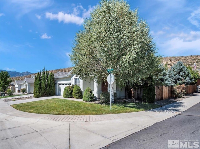 view of property hidden behind natural elements with a front lawn, driveway, fence, a garage, and stucco siding