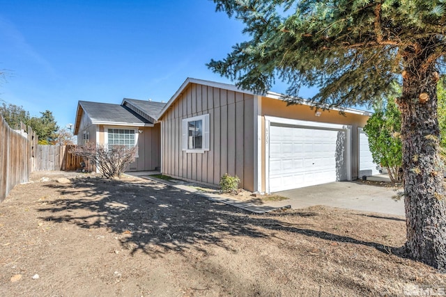 view of front of property featuring board and batten siding, an attached garage, driveway, and fence
