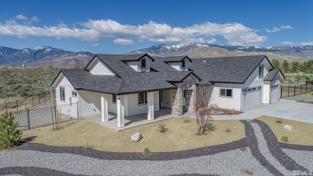 view of front of house featuring a mountain view, fence, roof with shingles, and driveway