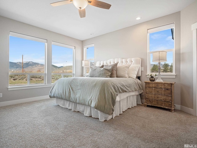 bedroom featuring baseboards, a ceiling fan, carpet flooring, and a mountain view