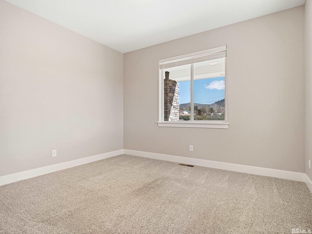 carpeted spare room featuring visible vents and baseboards