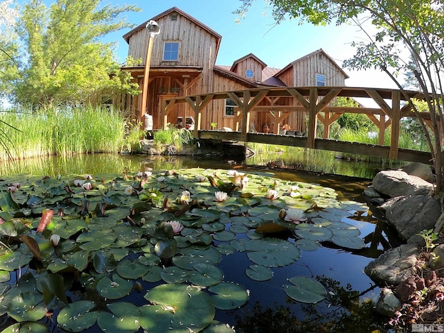 exterior space with board and batten siding, a barn, and a small pond
