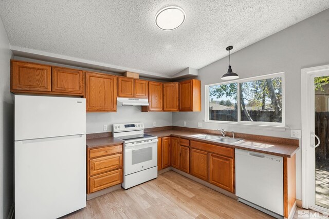 kitchen featuring under cabinet range hood, vaulted ceiling, a sink, white appliances, and a textured ceiling