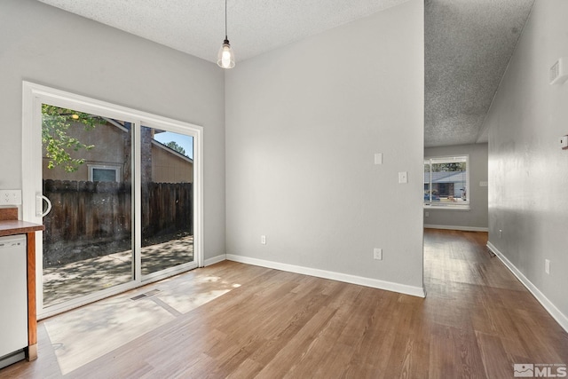 unfurnished dining area featuring visible vents, wood finished floors, and a textured ceiling