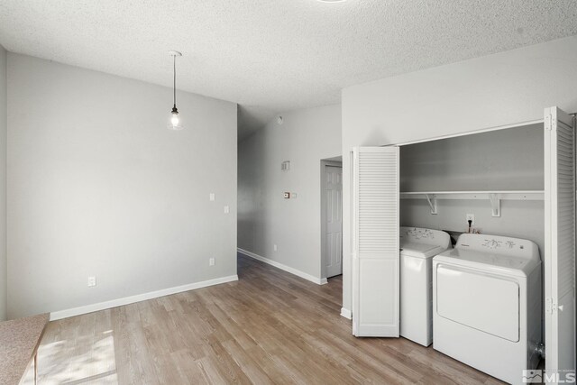 laundry area with laundry area, wood finished floors, baseboards, separate washer and dryer, and a textured ceiling