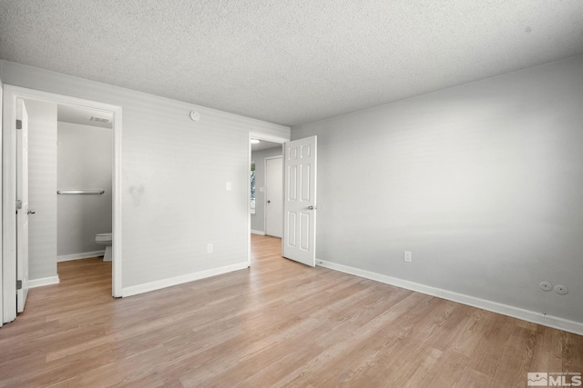 unfurnished bedroom featuring baseboards, visible vents, a textured ceiling, and light wood finished floors