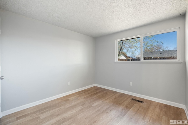 spare room with baseboards, light wood finished floors, and visible vents