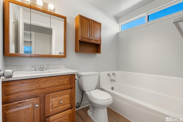 bathroom featuring wood finished floors, toilet, vanity, a bathing tub, and baseboards