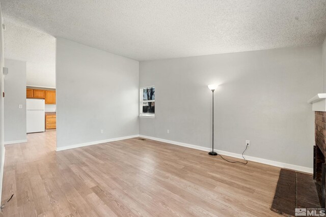 unfurnished living room with light wood-type flooring, a fireplace, and a textured ceiling