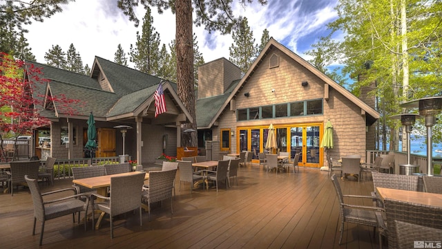 rear view of house featuring a wooden deck, outdoor dining space, and roof with shingles