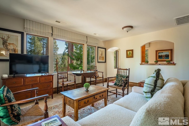 living room featuring baseboards, visible vents, and arched walkways