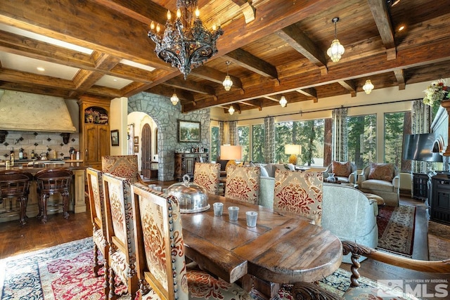 dining space featuring beamed ceiling, arched walkways, wood finished floors, and wood ceiling
