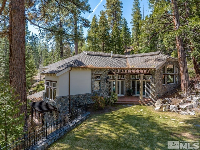 rear view of property with a lawn, french doors, and stone siding
