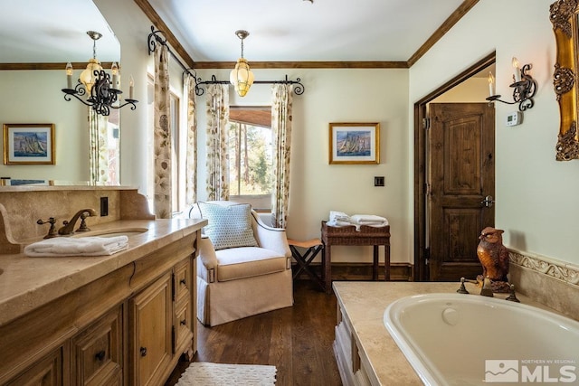 full bathroom with wood finished floors, vanity, a notable chandelier, a garden tub, and crown molding