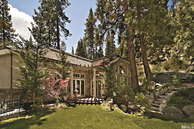 exterior space featuring a patio, a yard, and stone siding