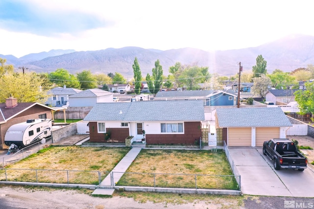 view of front of house featuring a fenced front yard, a front lawn, a residential view, concrete driveway, and a mountain view
