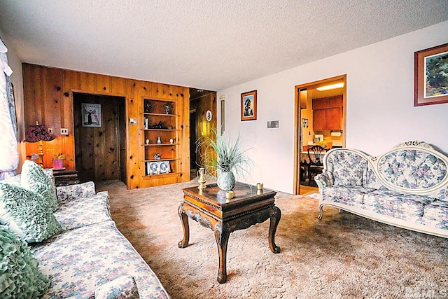 living area featuring wooden walls, carpet floors, and a textured ceiling