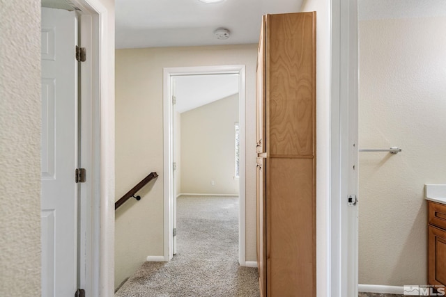 hall featuring baseboards, light colored carpet, and an upstairs landing