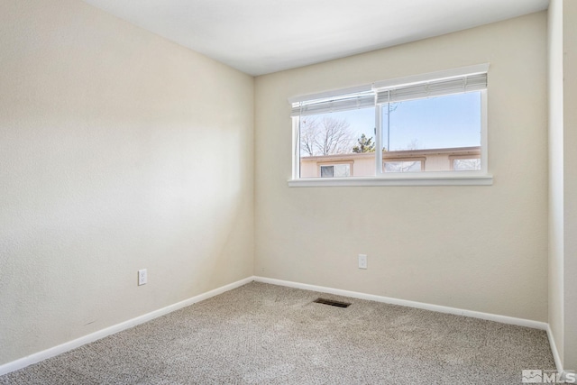 carpeted spare room with visible vents and baseboards