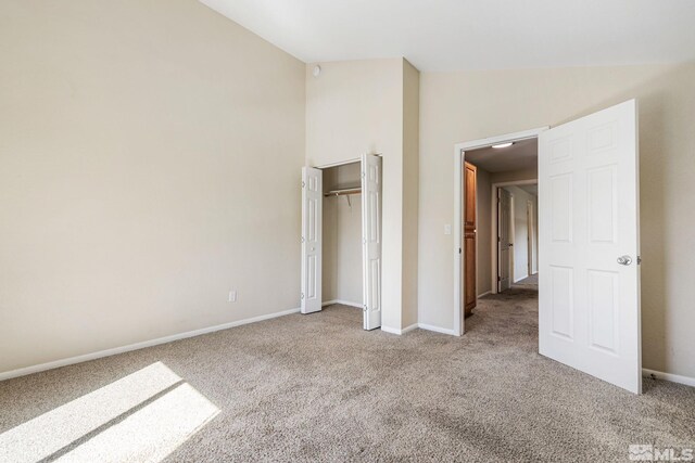 unfurnished bedroom featuring baseboards, lofted ceiling, a closet, and carpet