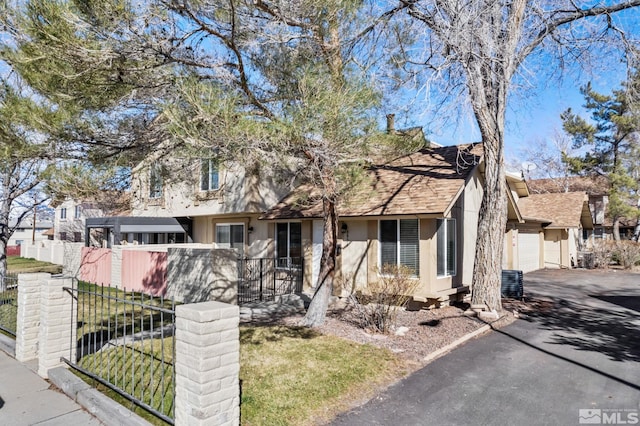 view of property featuring central AC unit, stucco siding, driveway, fence private yard, and a garage