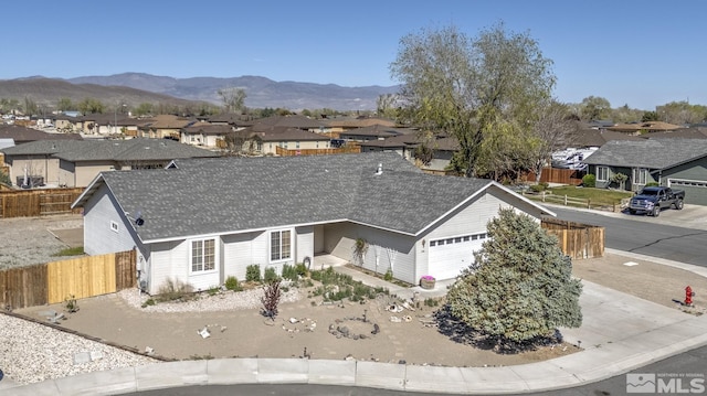 ranch-style home with an attached garage, fence, a mountain view, and a residential view