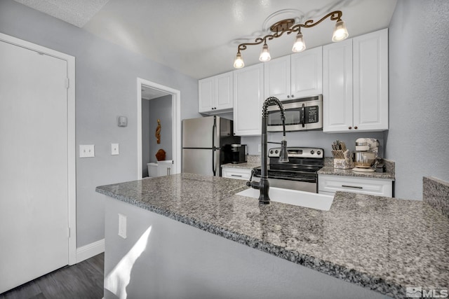 kitchen featuring white cabinets, dark wood-style floors, baseboards, light stone counters, and appliances with stainless steel finishes
