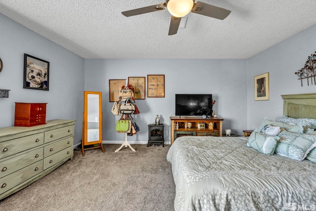 bedroom with light carpet, a wood stove, a textured ceiling, and ceiling fan