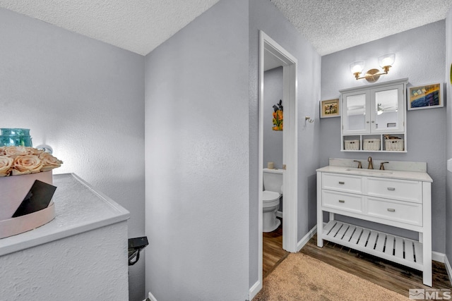 bathroom featuring baseboards, wood finished floors, a textured ceiling, and toilet