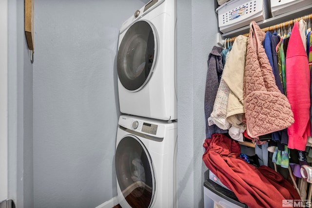 laundry room with a textured wall, stacked washer and clothes dryer, and laundry area
