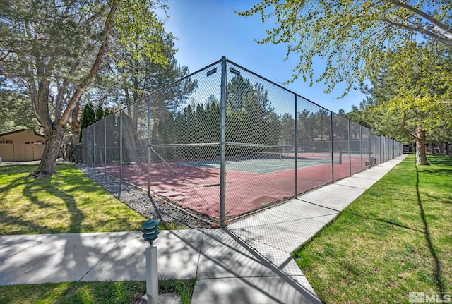 view of tennis court with fence and a lawn