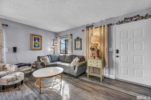 living area with baseboards, wood finished floors, and a textured ceiling