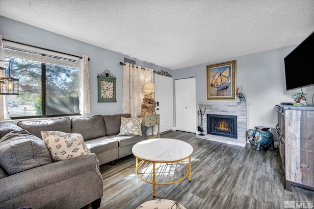 living room featuring wood finished floors, a textured ceiling, and a lit fireplace