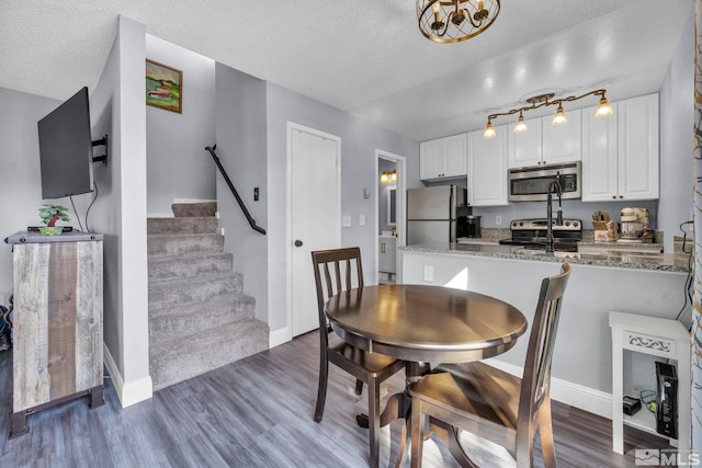 dining space with dark wood-type flooring, stairway, a textured ceiling, and baseboards