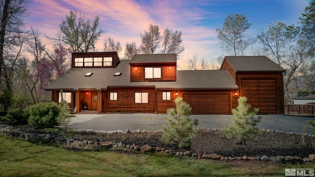 view of front of home with an attached garage, aphalt driveway, and a yard