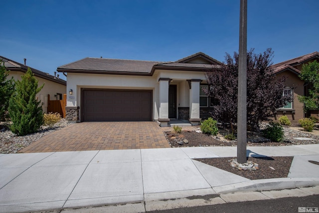 view of front of home with stucco siding, a tile roof, decorative driveway, stone siding, and a garage
