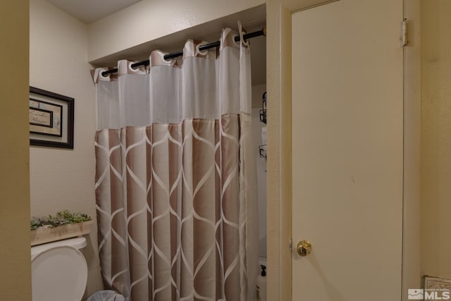 bathroom featuring toilet and curtained shower