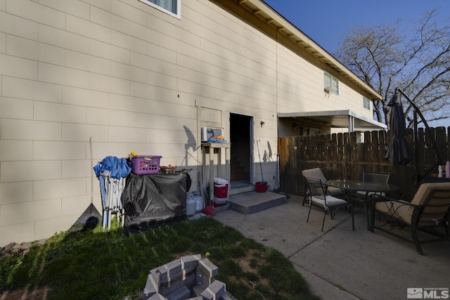 rear view of property with fence, outdoor dining area, concrete block siding, and a patio
