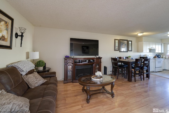 living area with a textured ceiling, light wood finished floors, and a fireplace