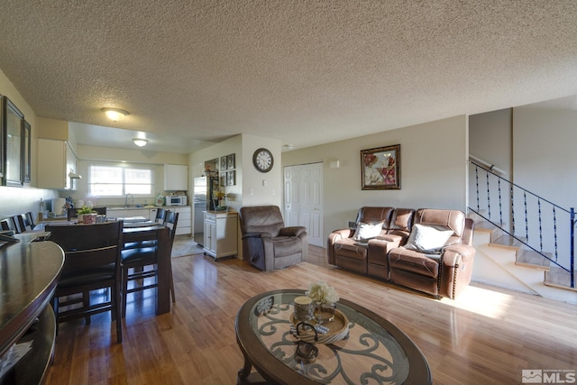living area with wood finished floors, a textured ceiling, and stairway