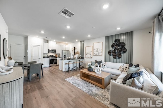 living area with light wood-style floors, visible vents, and recessed lighting